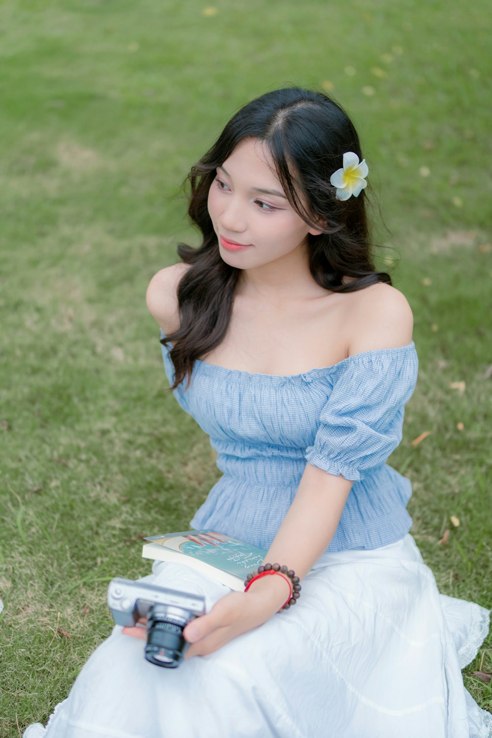 a woman in a blue dress sitting on the grass