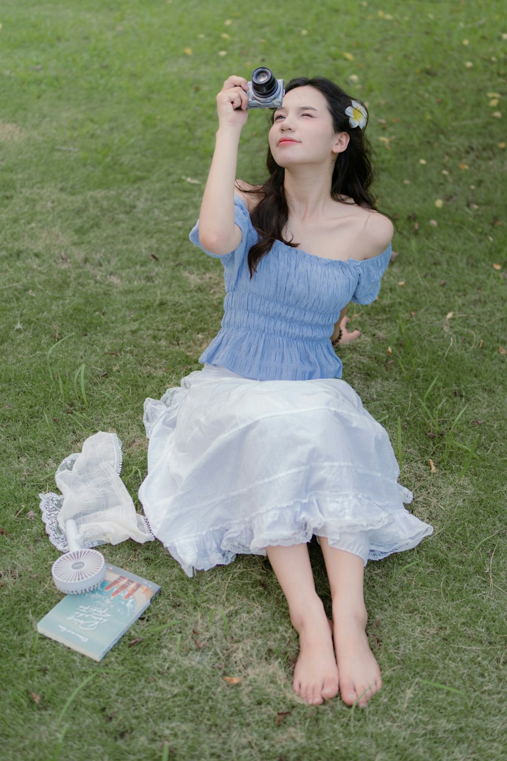 a woman sitting on the grass with a camera