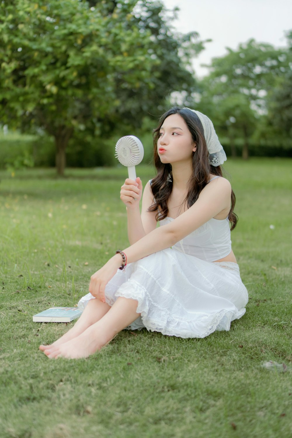 a woman in a white dress sitting on the grass