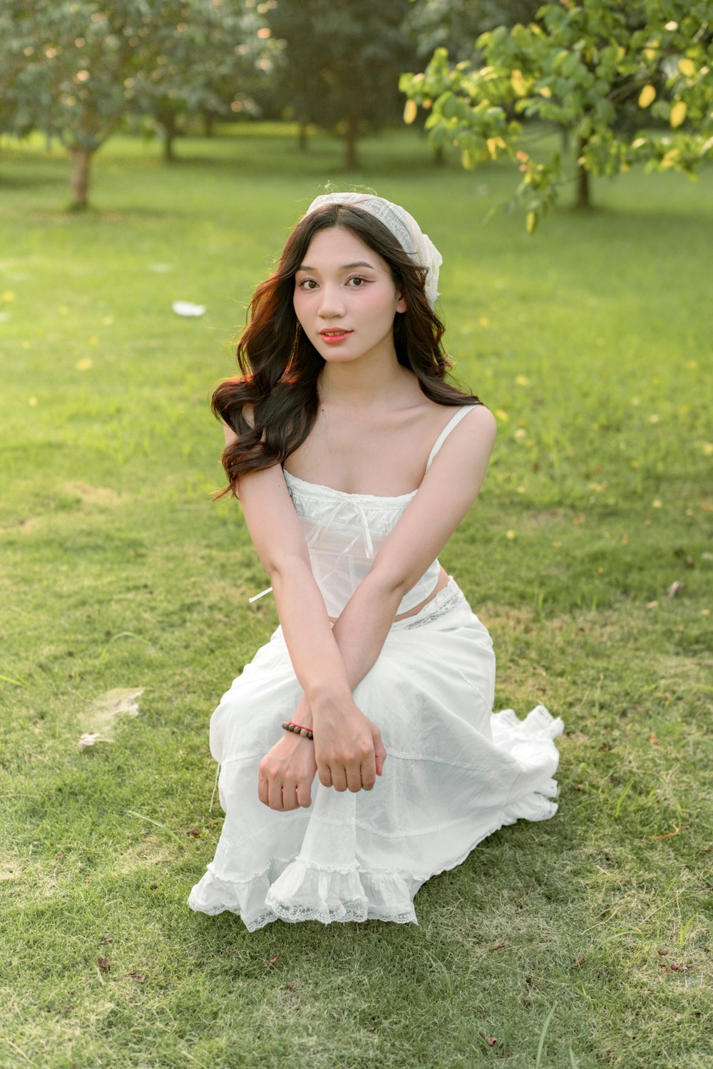 a woman in a white dress sitting on the grass