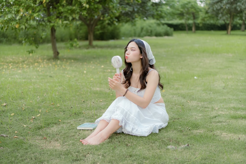 a woman in a white dress sitting on the grass