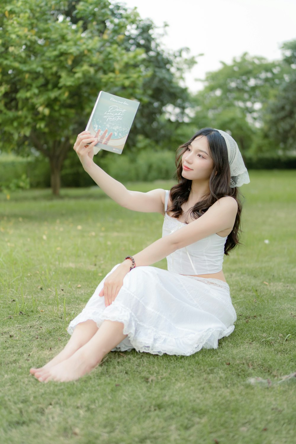 a woman sitting in the grass holding a book