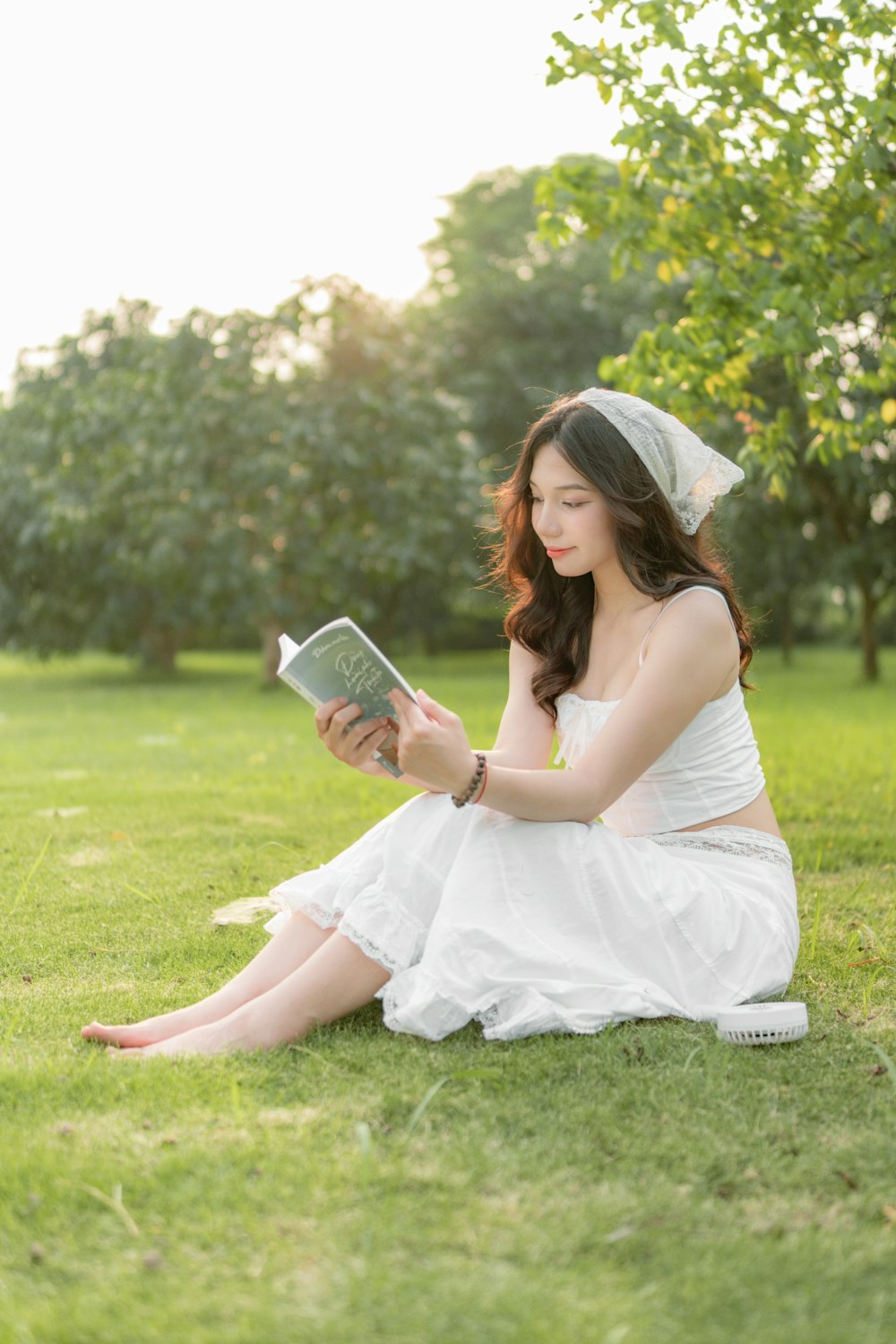a woman sitting in the grass reading a book