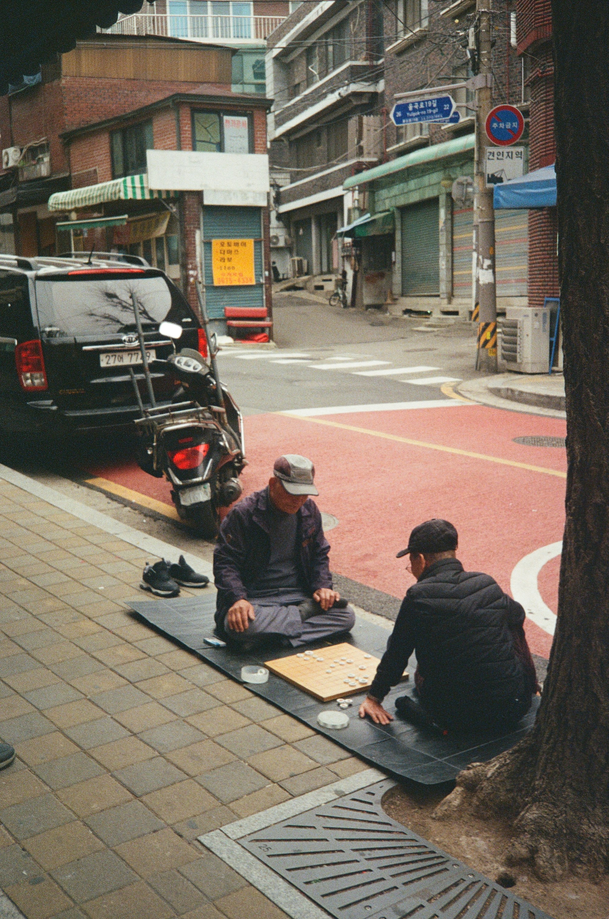 a couple of men sitting on top of a sidewalk
