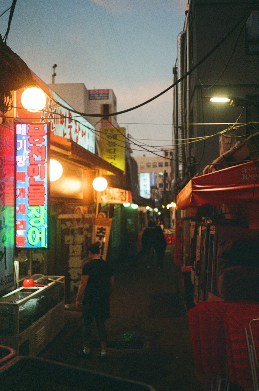 a narrow alley way with neon signs on the buildings