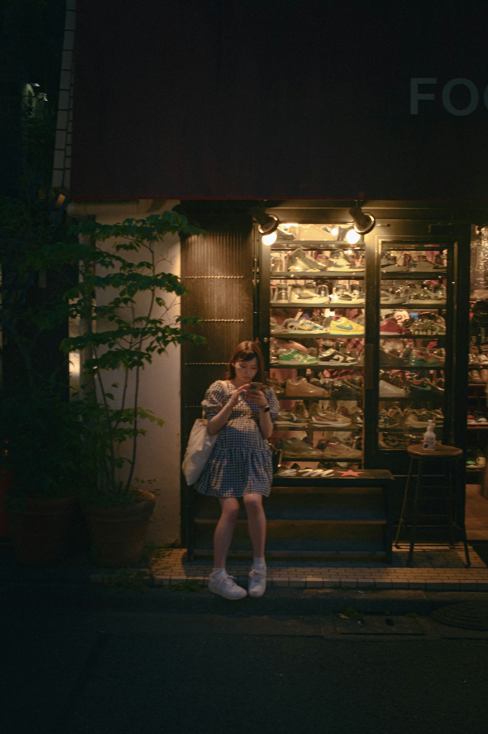 una mujer parada frente a una tienda por la noche