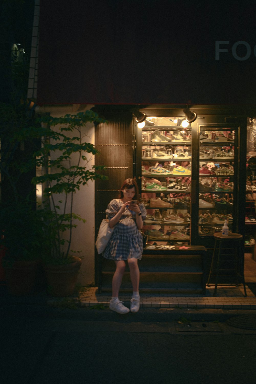 a woman standing in front of a store at night