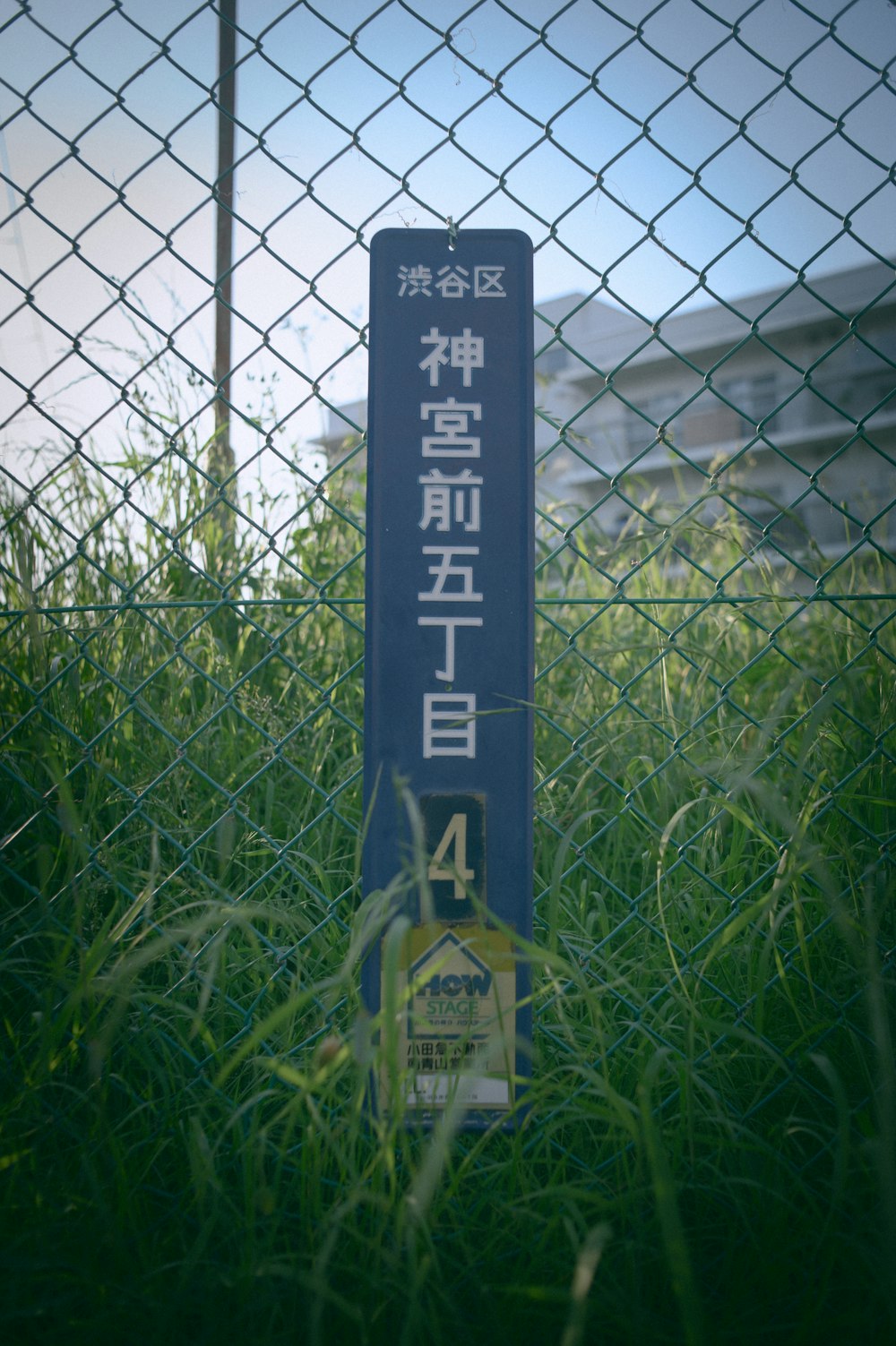 a sign that is in the grass behind a fence