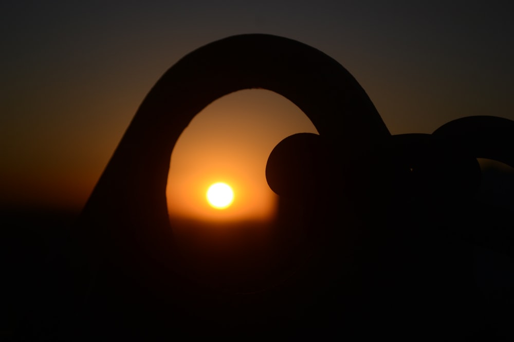 the sun is setting behind a silhouette of a hand