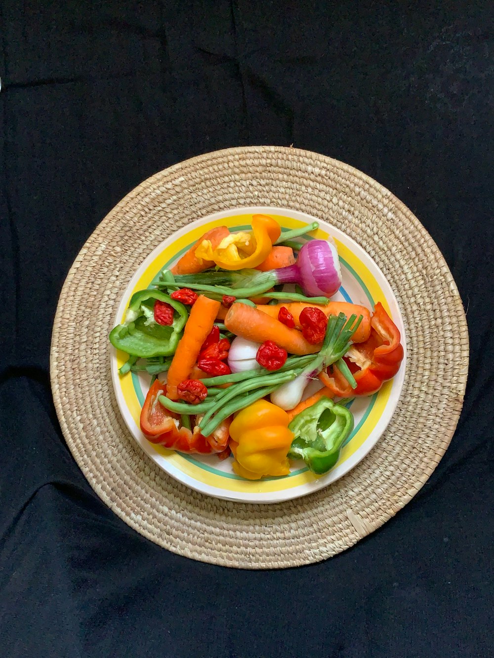 a plate of colorful vegetables on a black background