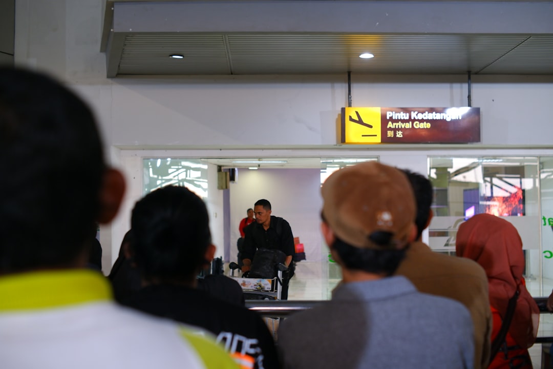 a group of people standing in front of a store, waiting for someone at the airport arrivals terminal.