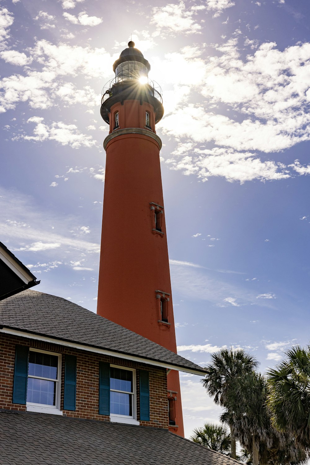 a red light house with the sun shining through the clouds