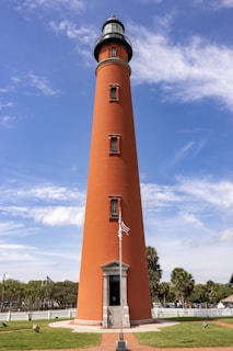 a tall light house sitting on top of a lush green field