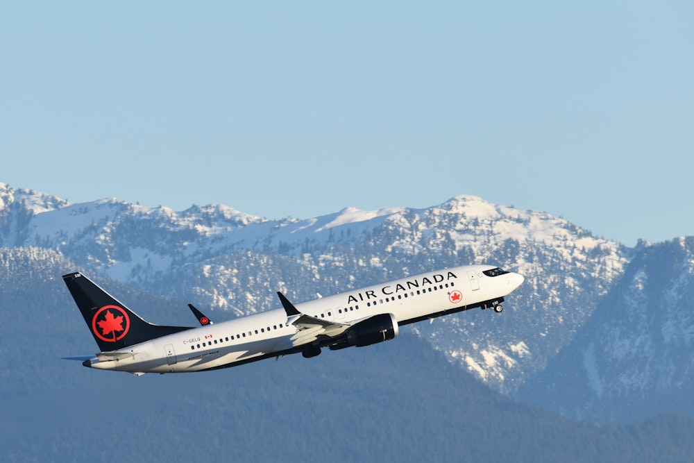 an air canada airplane flying over a mountain range