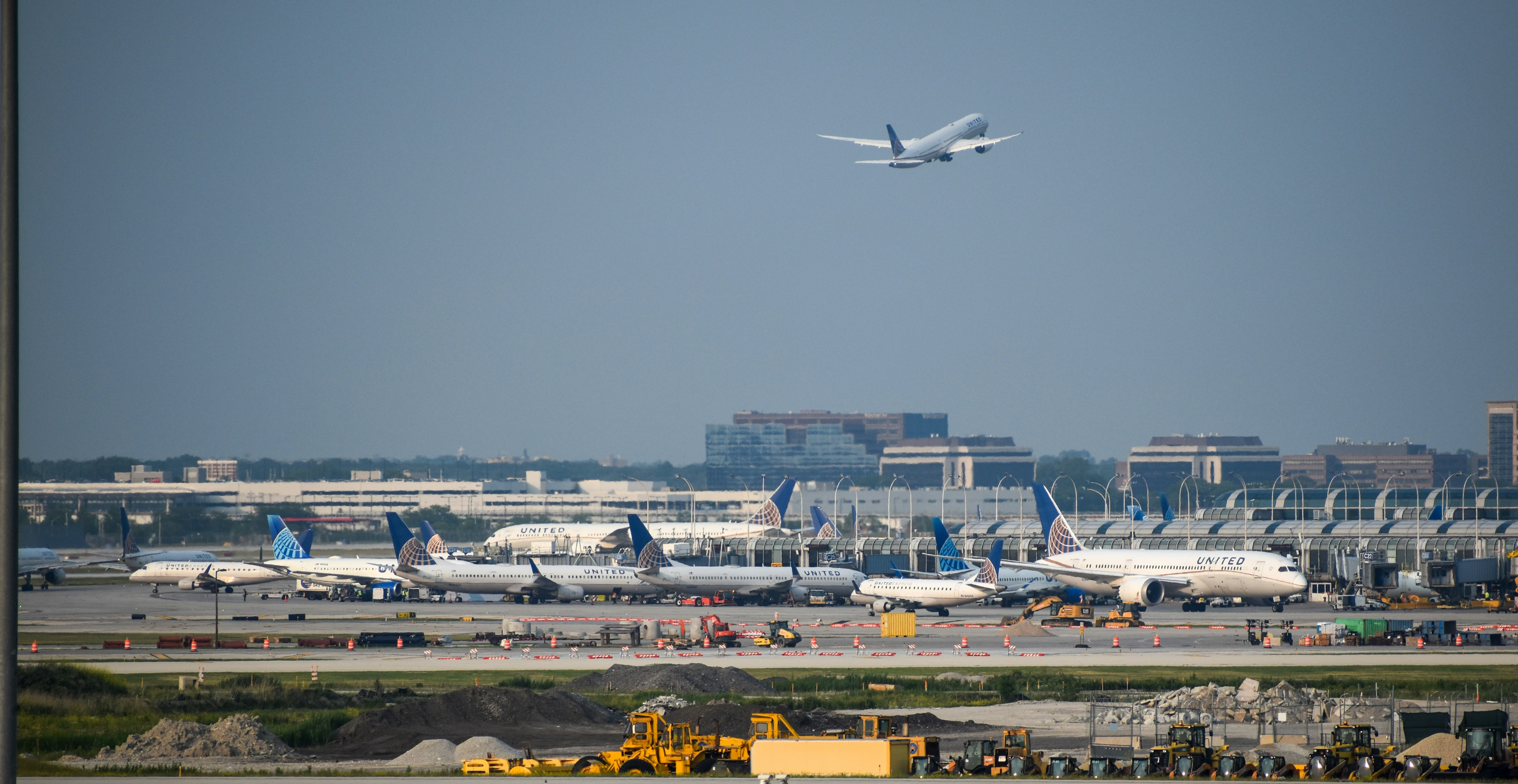 a large jetliner flying over an airport runway, United Airlines jets Chicago O