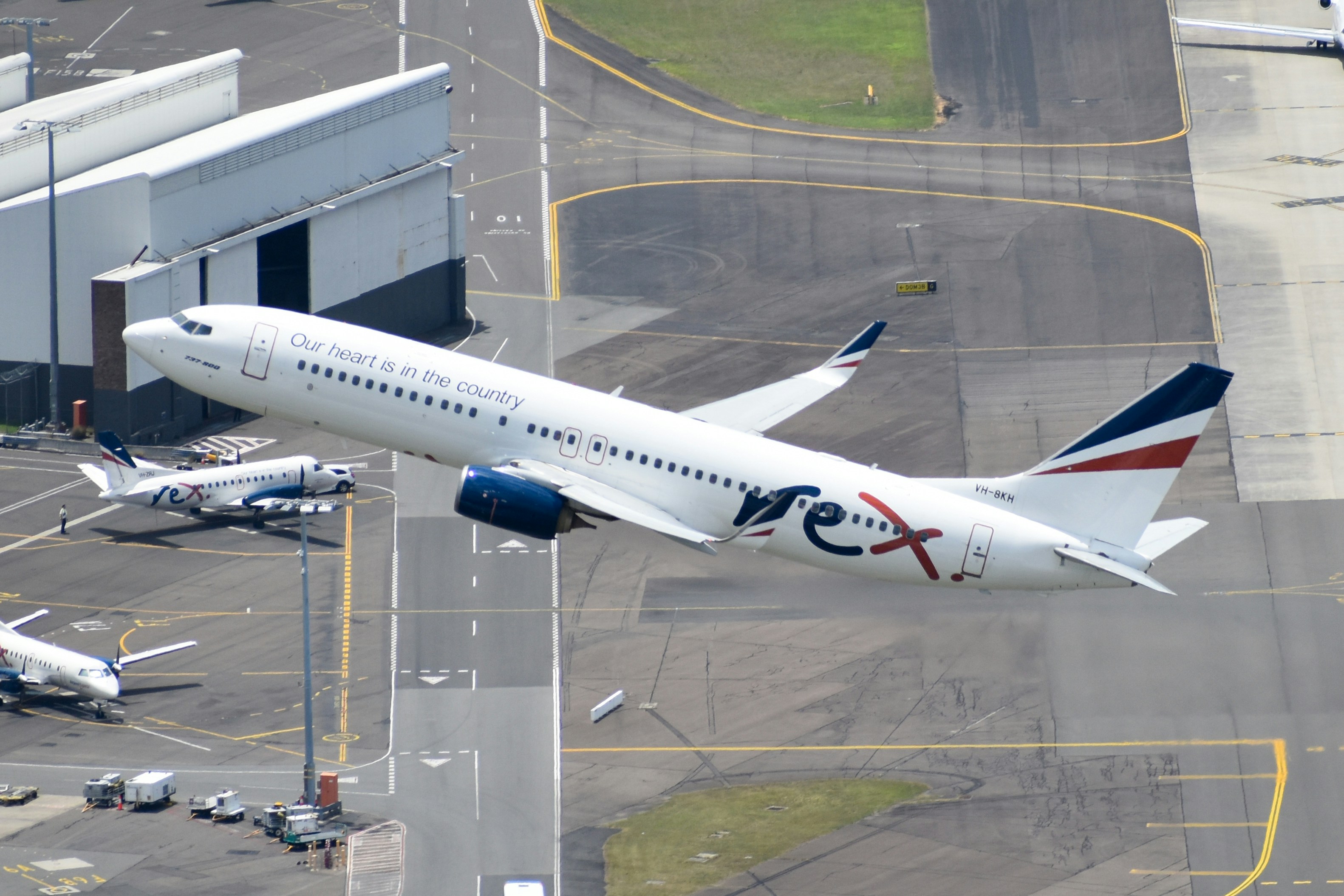 a large passenger jet flying over a runway, Rex 737-800 departing Sydney Airport