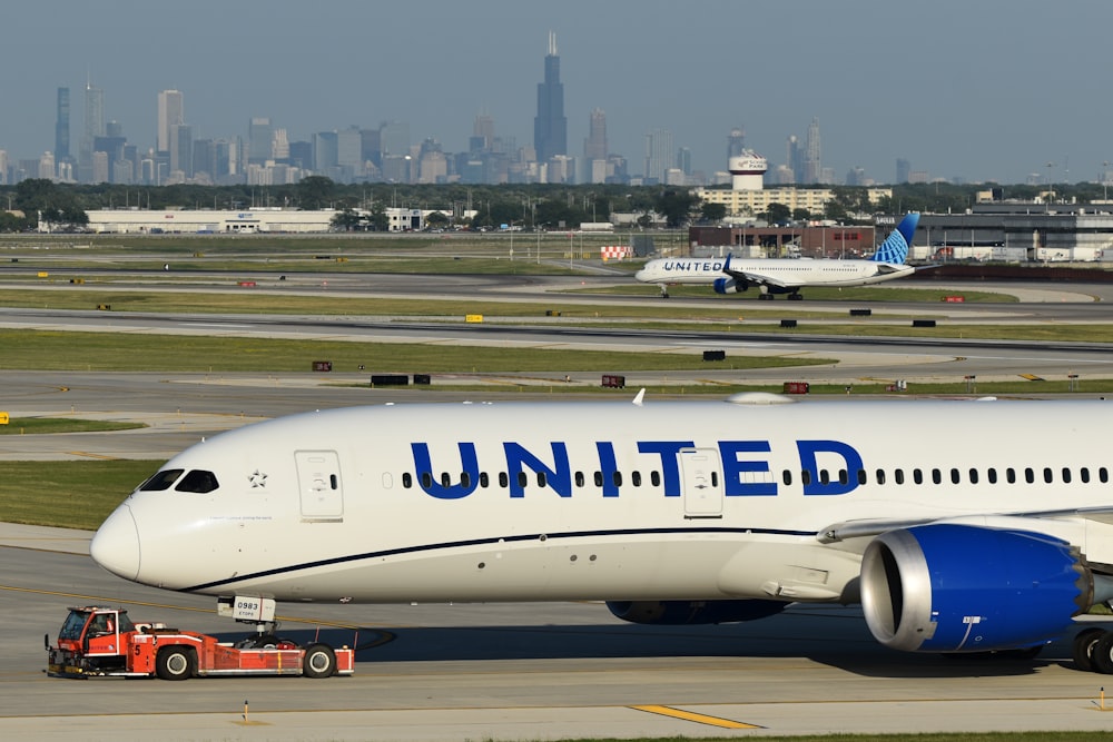 Un avión de United Airlines en una pista con una ciudad al fondo