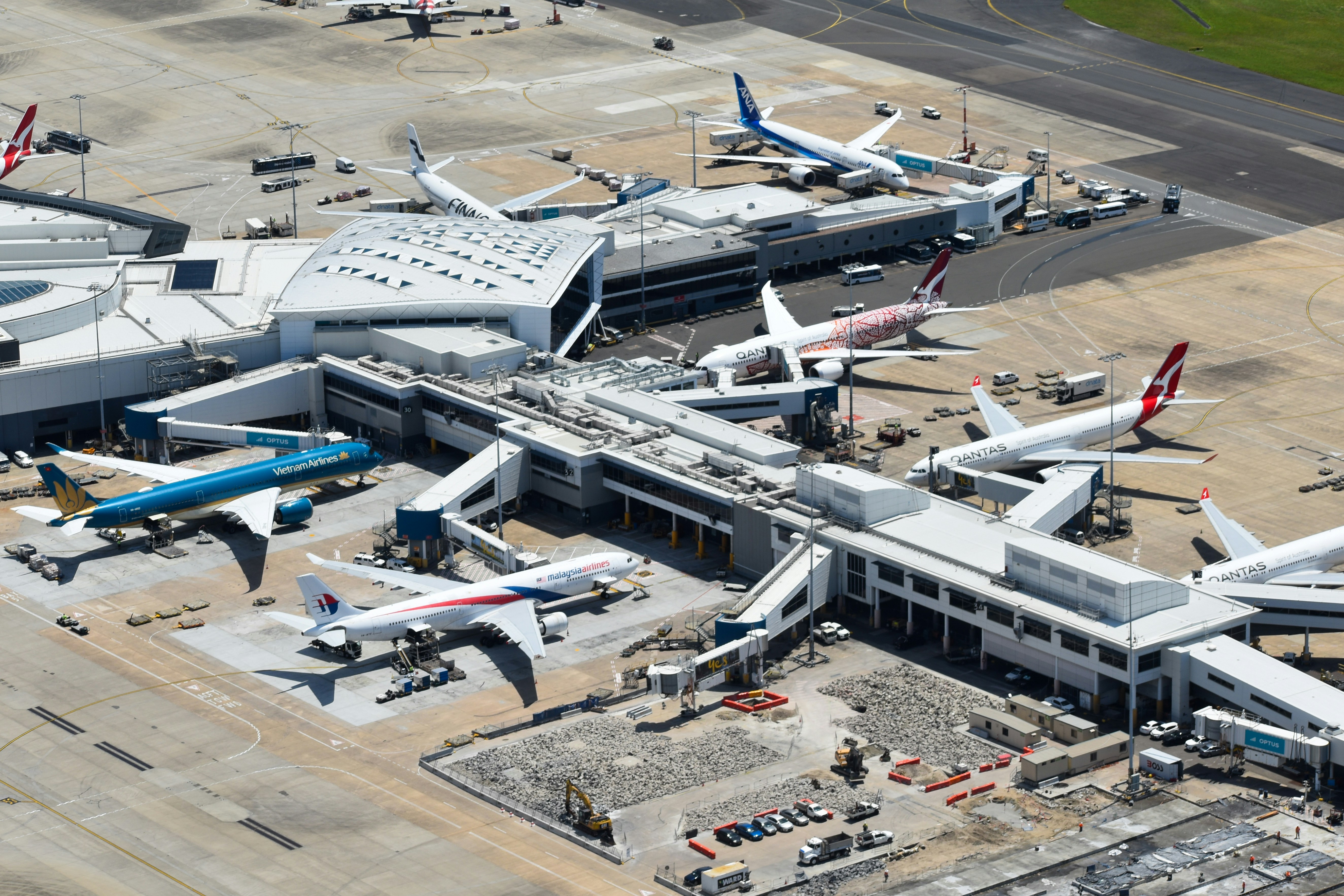 An aerial view of a packed airport terminal with passengers looking at departure boards, some with worried expressions, reflecting travel anxiety.