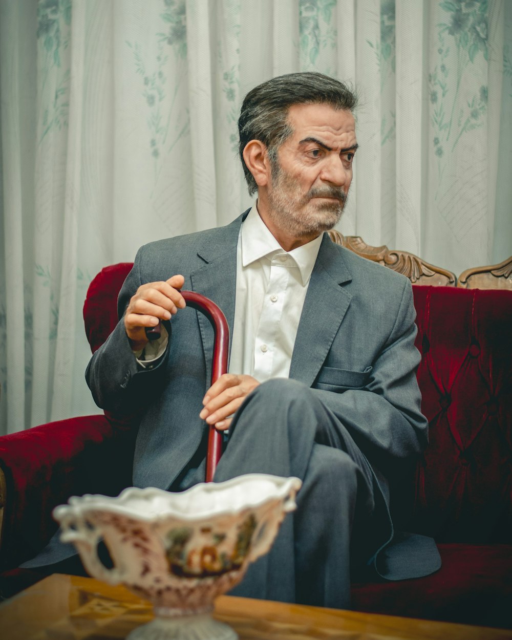 a man sitting on a couch holding a cane