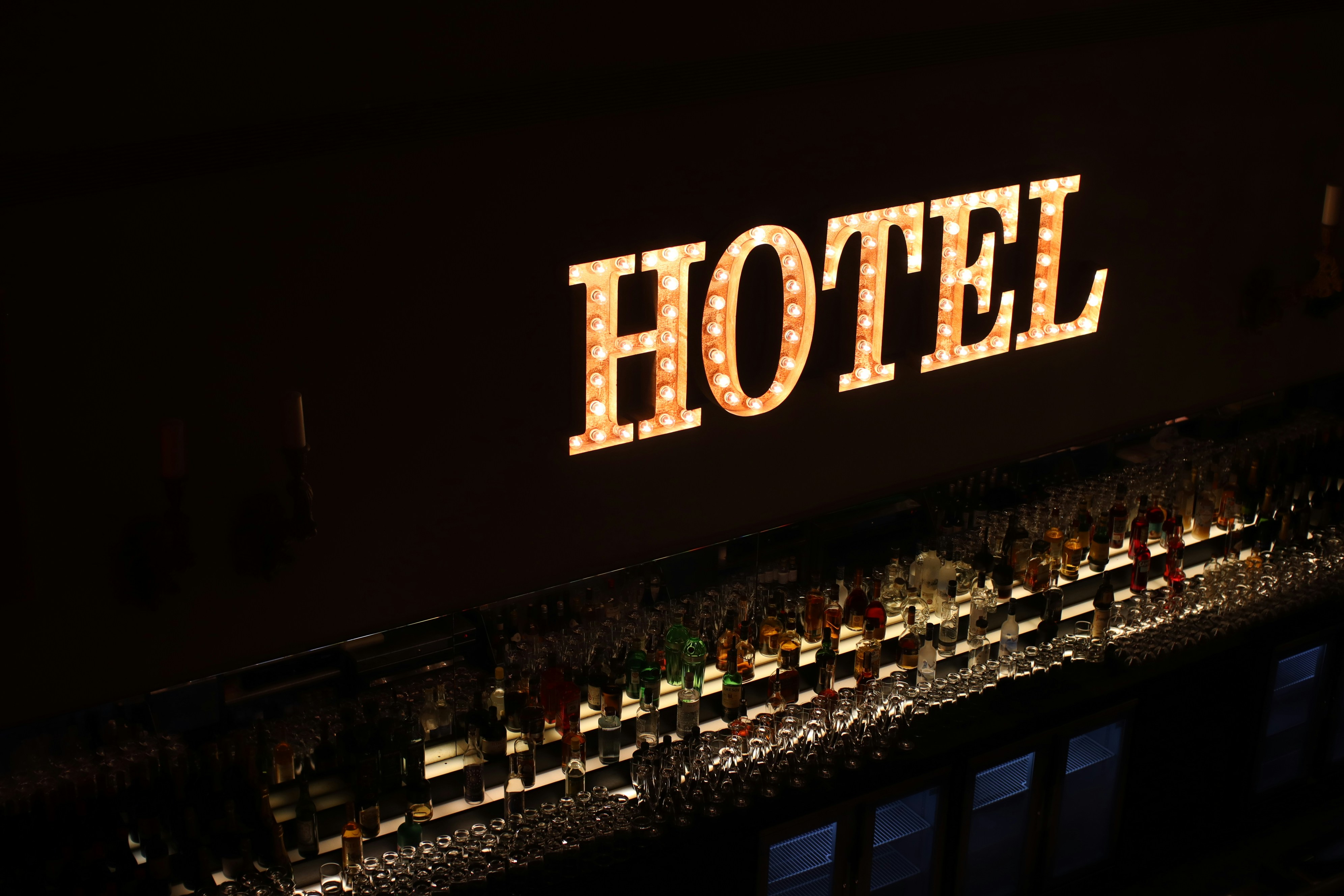 a lighted hotel sign above a bar filled with liquor bottles