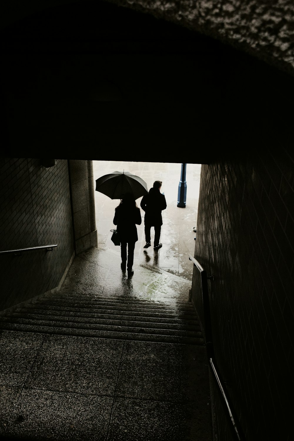 two people walking up a flight of stairs with an umbrella