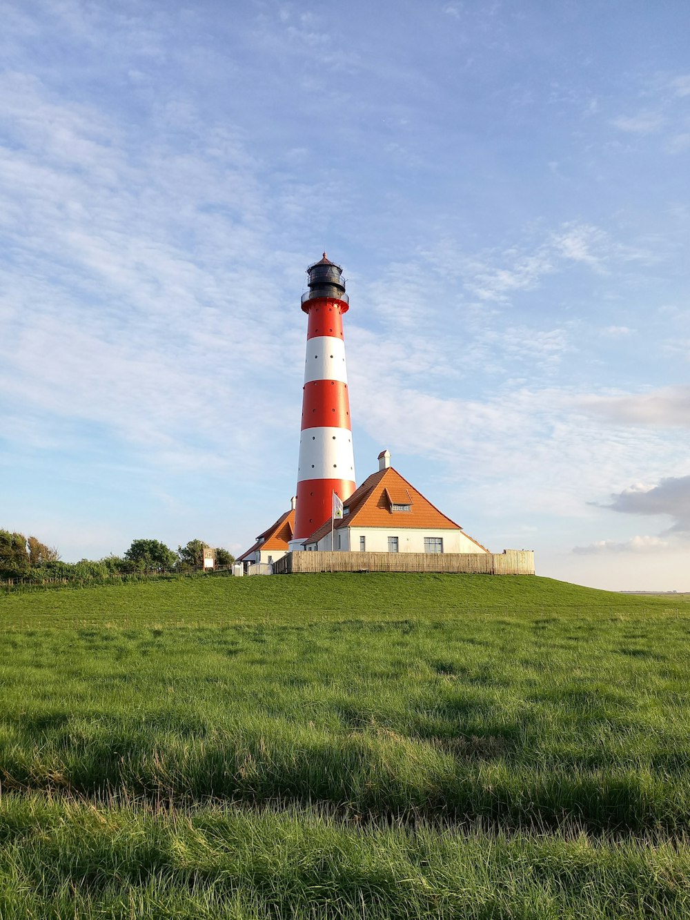 a red and white lighthouse on a grassy hill