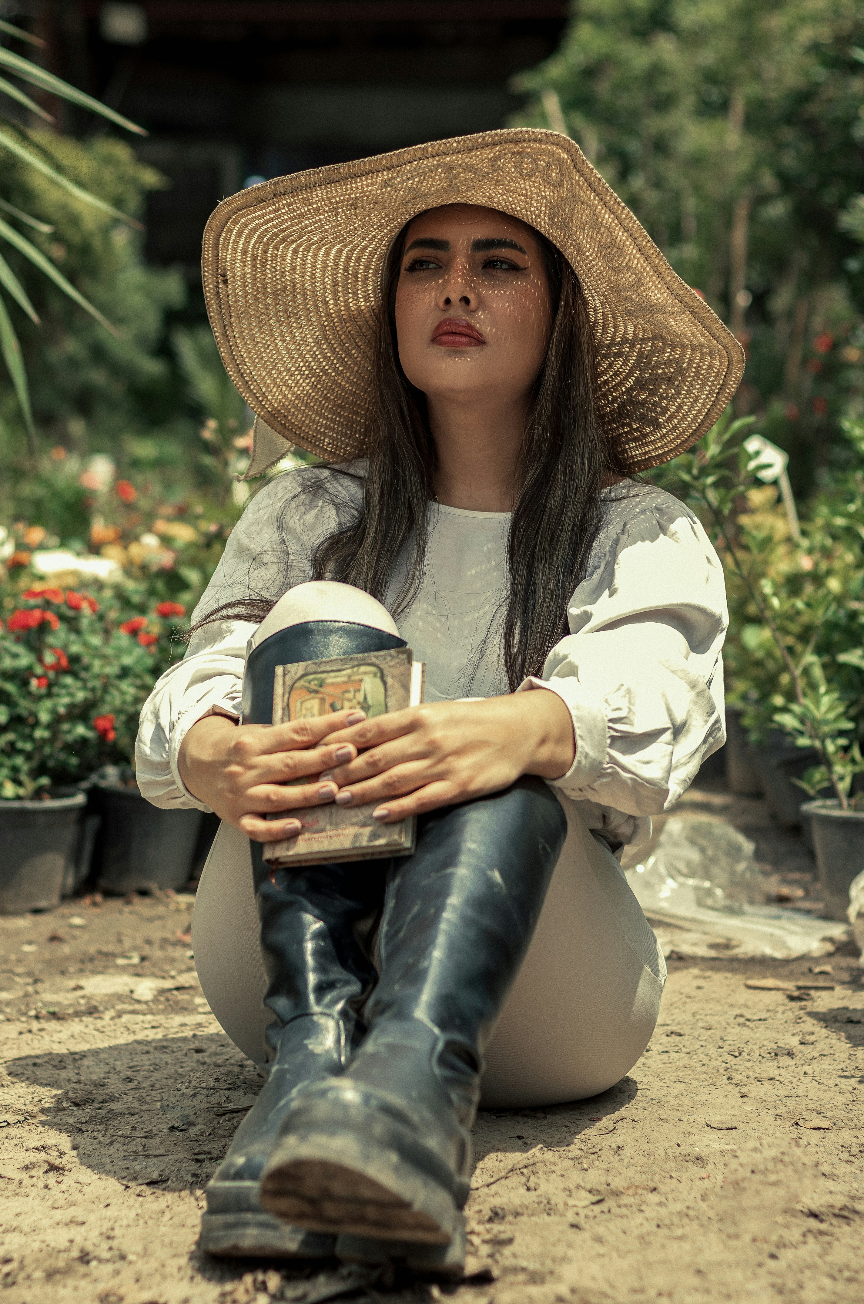 a woman sitting on the ground wearing a hat