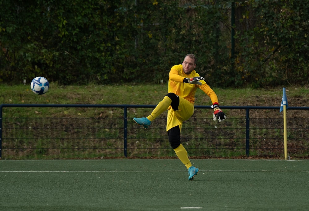 a man in a yellow uniform kicking a soccer ball