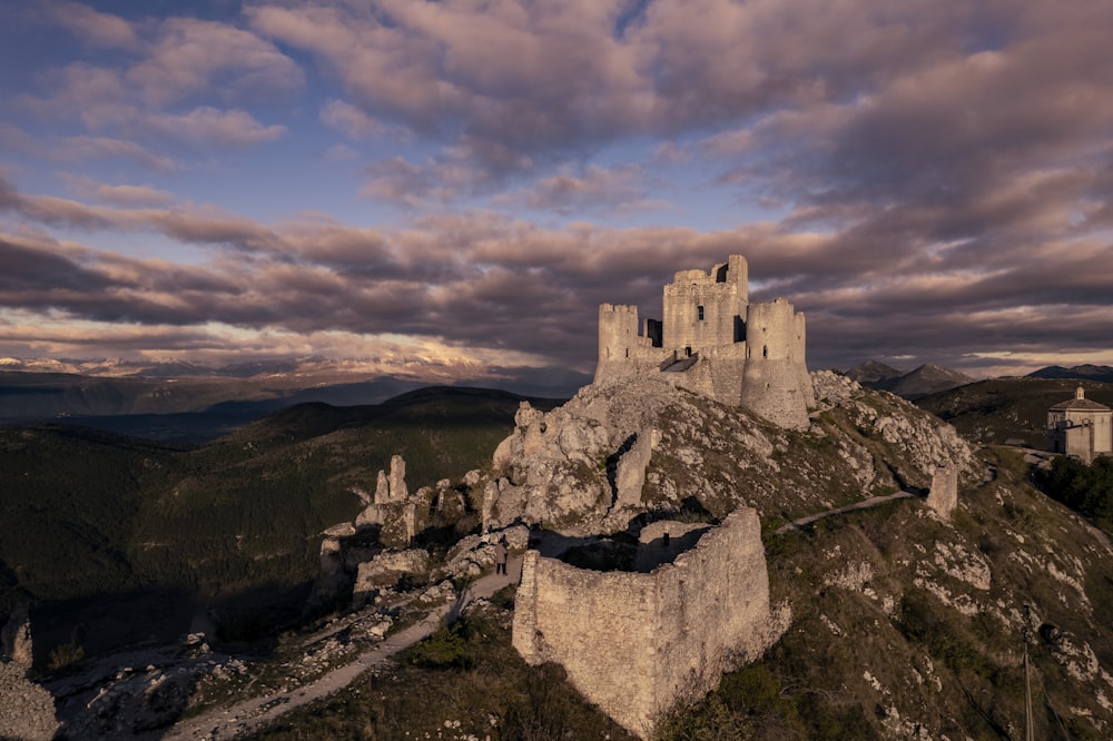 a castle sitting on top of a mountain under a cloudy sky
