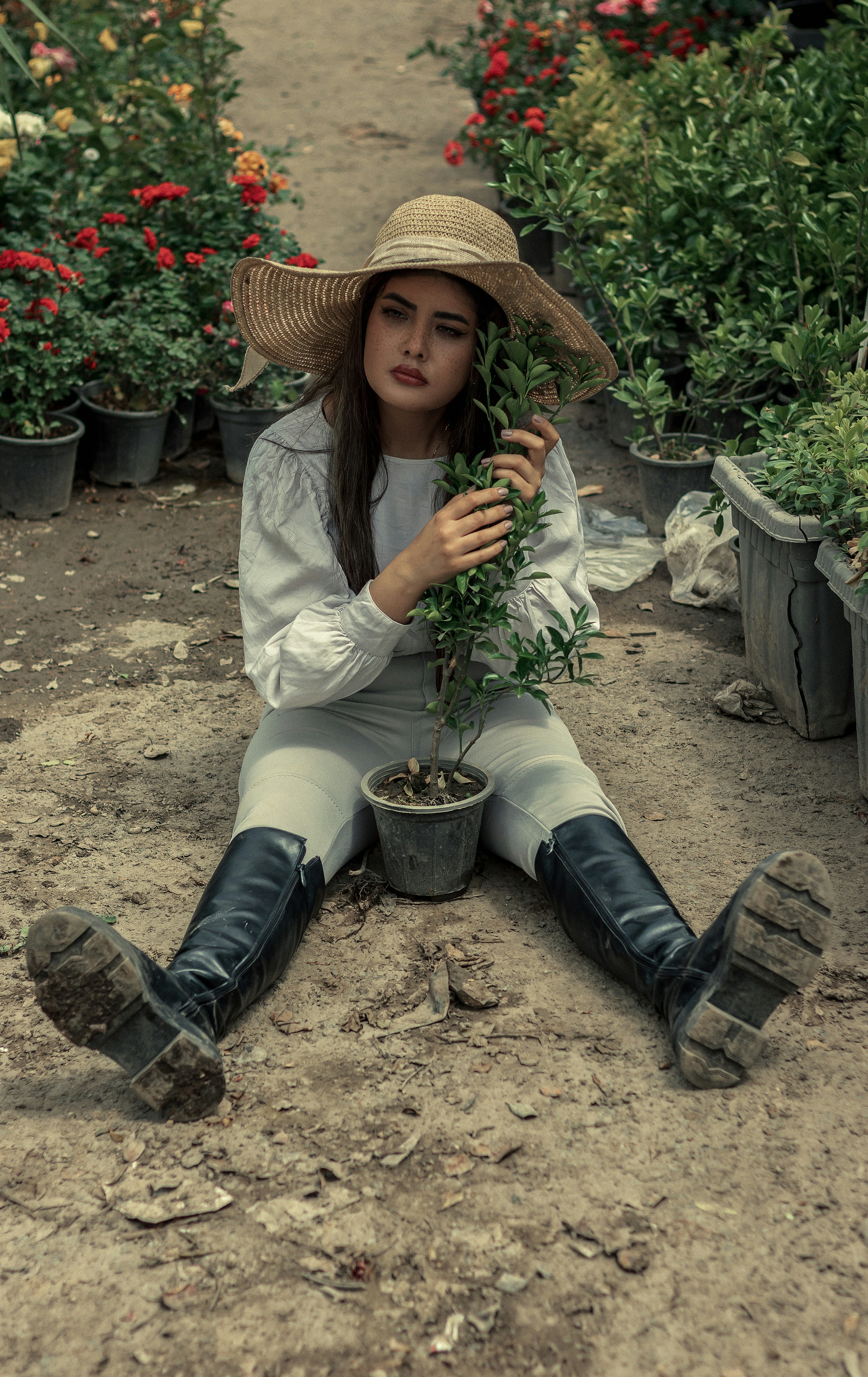 a woman sitting on the ground holding a plant
