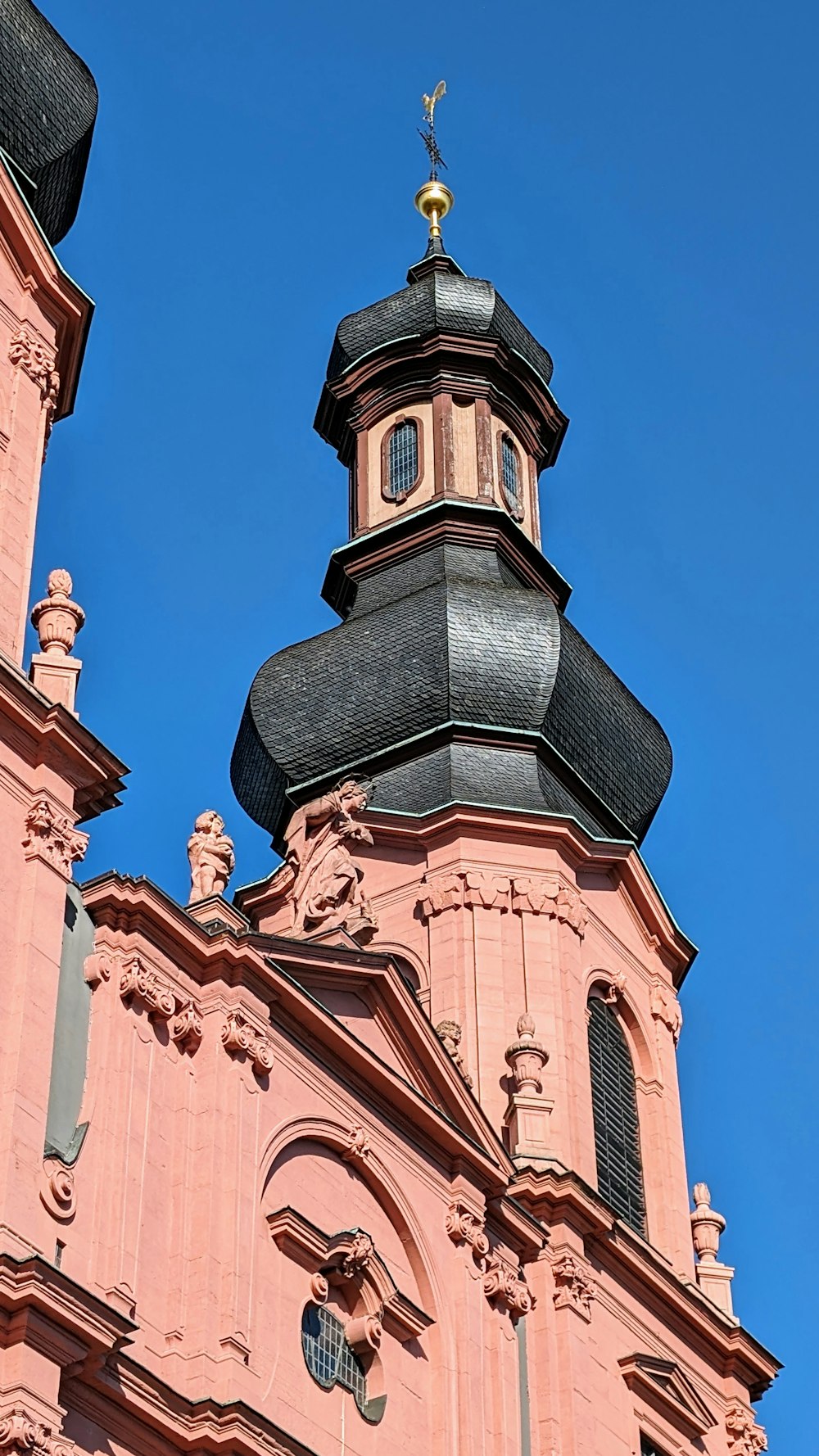 a tall pink building with a clock on it's side