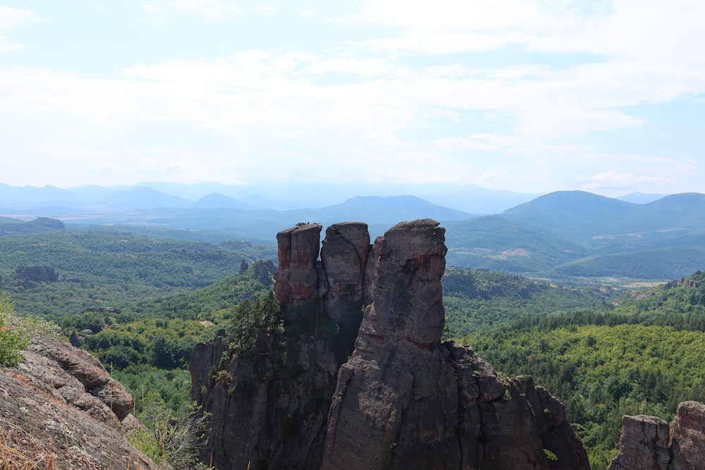 a rocky outcropping with trees and mountains in the background