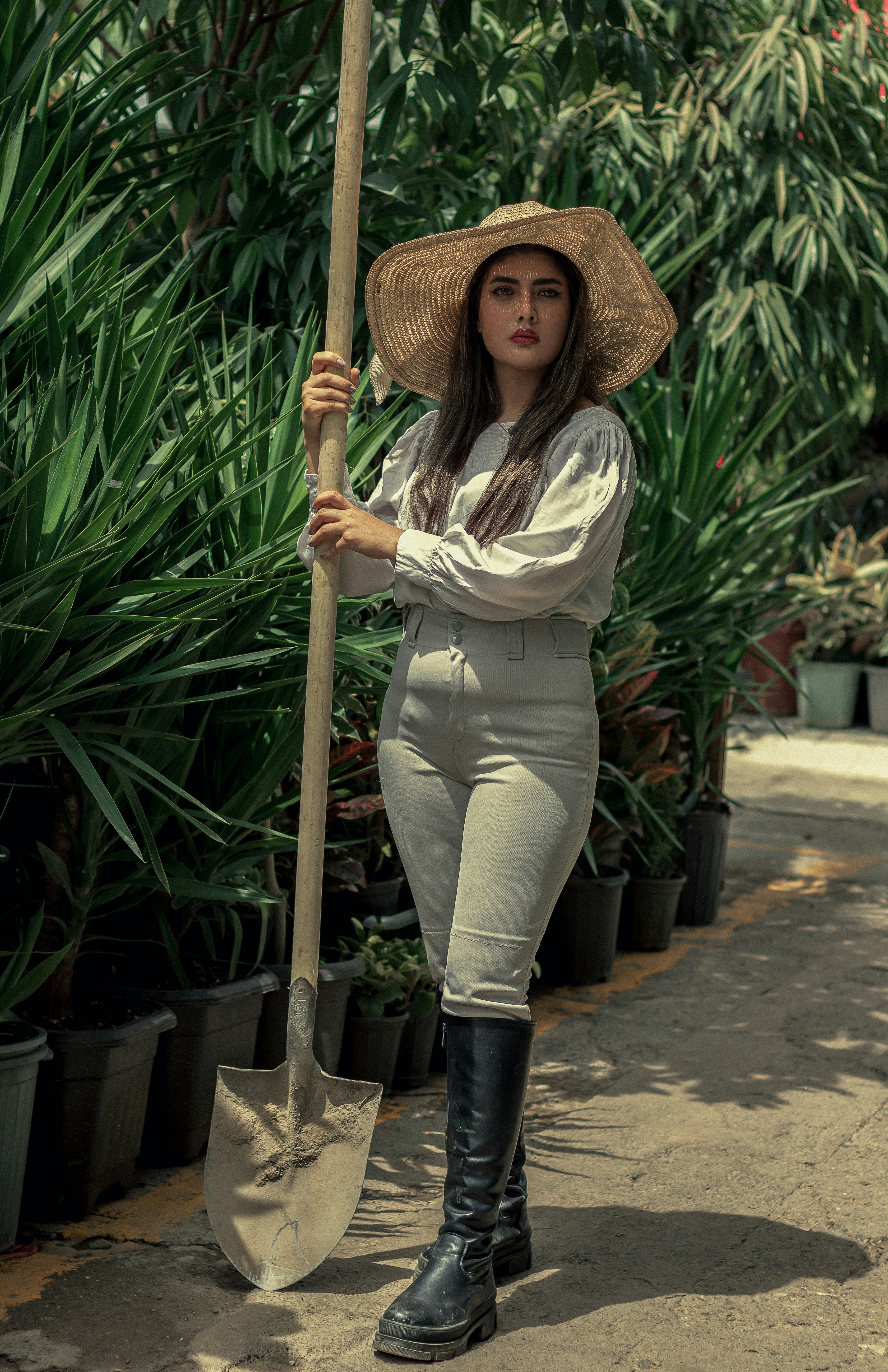 a woman in a straw hat is holding a shovel