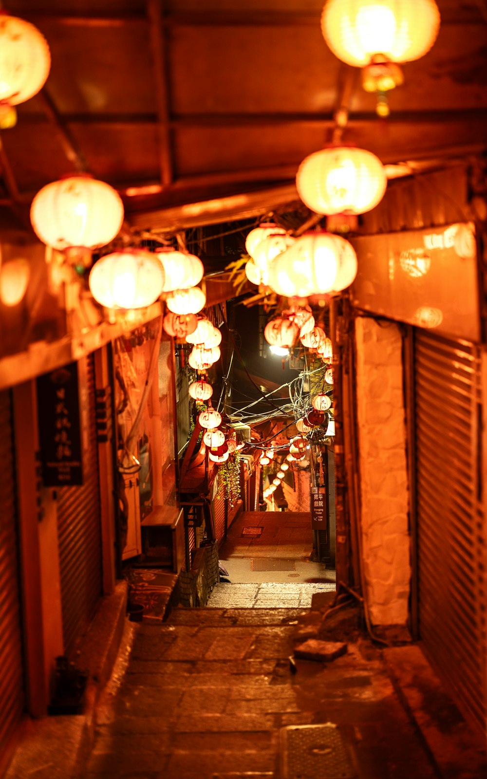a narrow alley with lanterns hanging from the ceiling