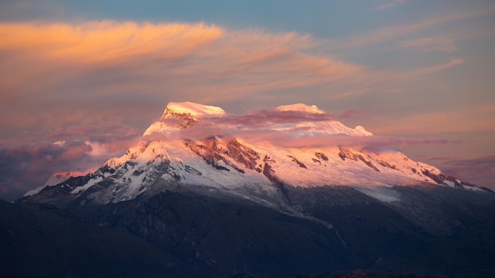 a mountain covered in snow under a cloudy sky