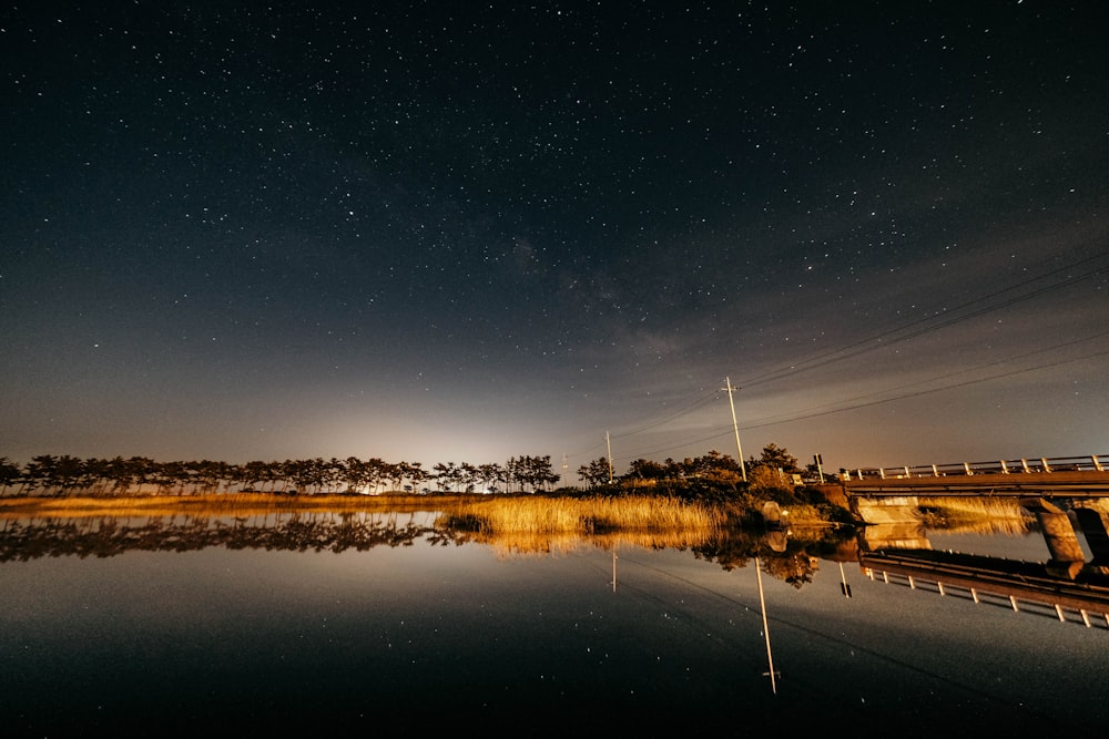 the night sky is reflected in the still water of a lake