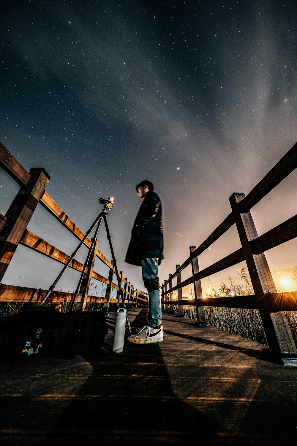 a man standing on a wooden bridge at night