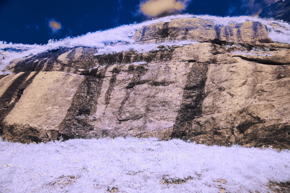 a snow covered rock face with a blue sky in the background