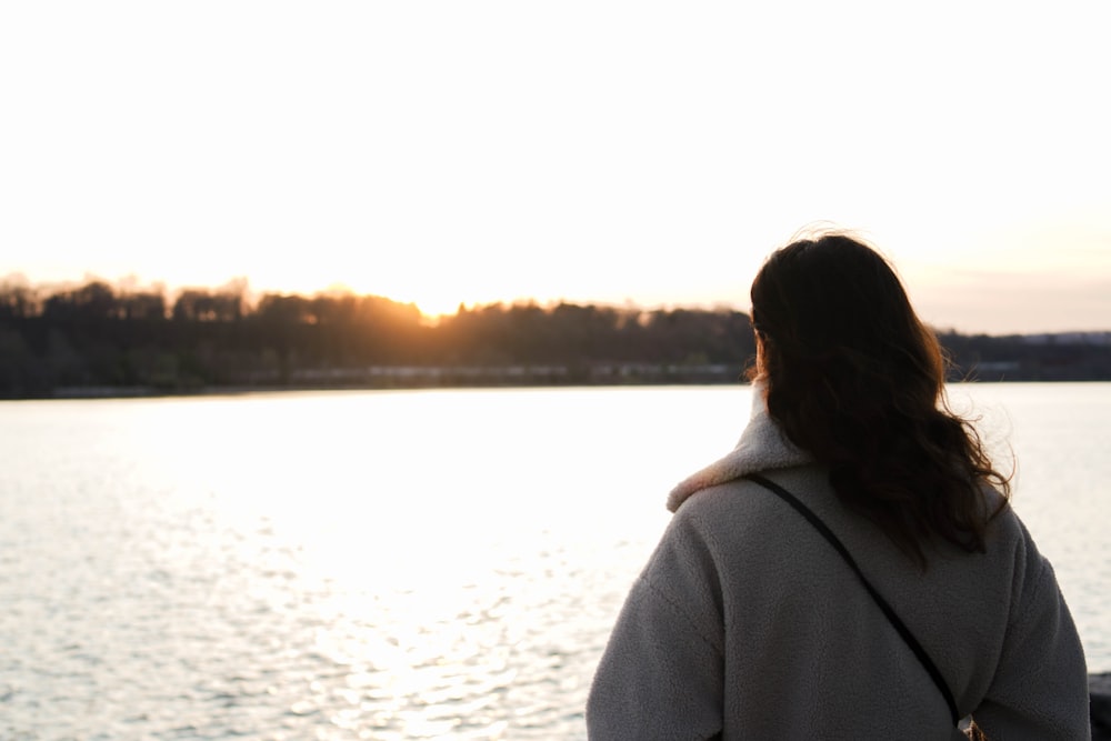 a woman standing on a pier looking at the water