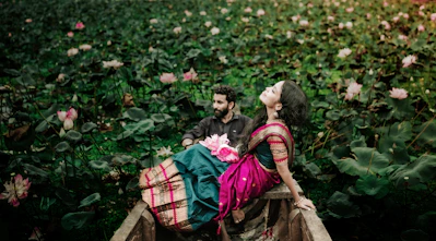 a man and a woman sitting on a boat in a field of flowers