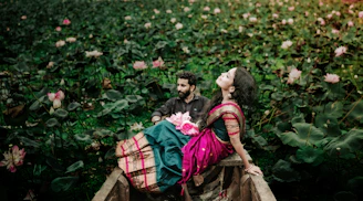 a man and a woman sitting on a boat in a field of flowers
