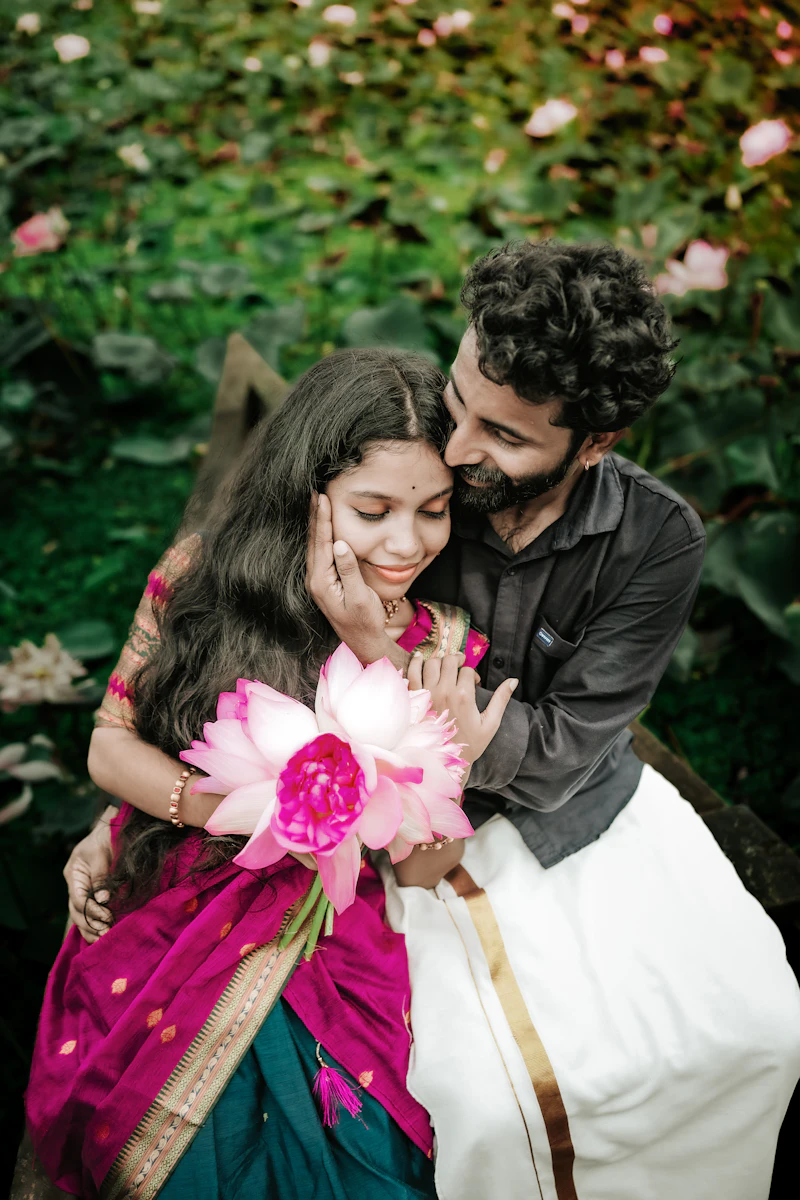 Priya holding pink lotus flowers while Arjun hugs her from behind