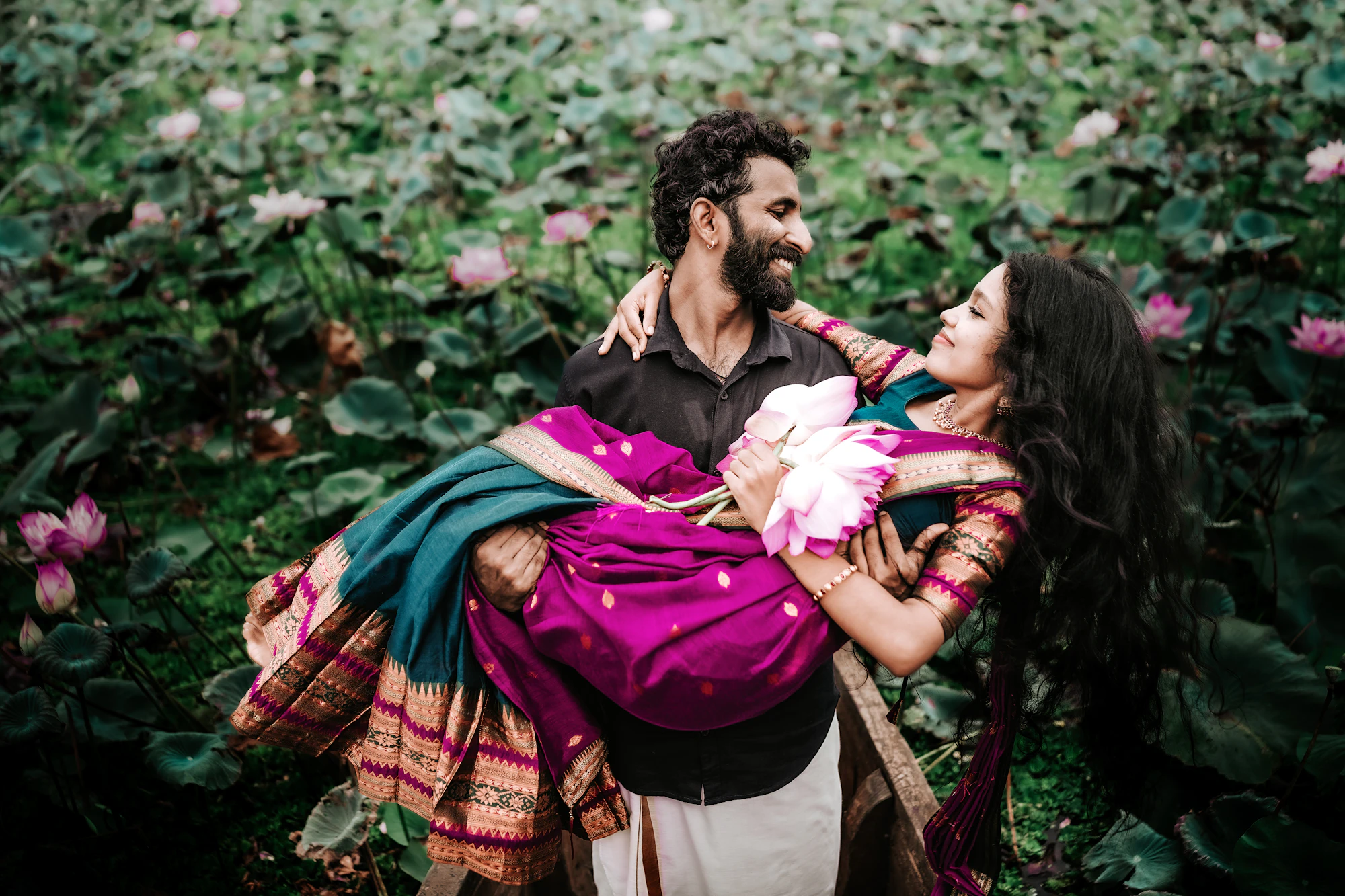 Arjun carrying Priya, both laughing, among lotus leaves