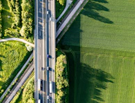 an aerial view of a highway in the middle of a green field