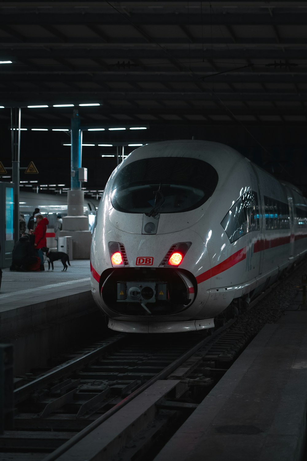 a white train traveling down train tracks next to a loading platform