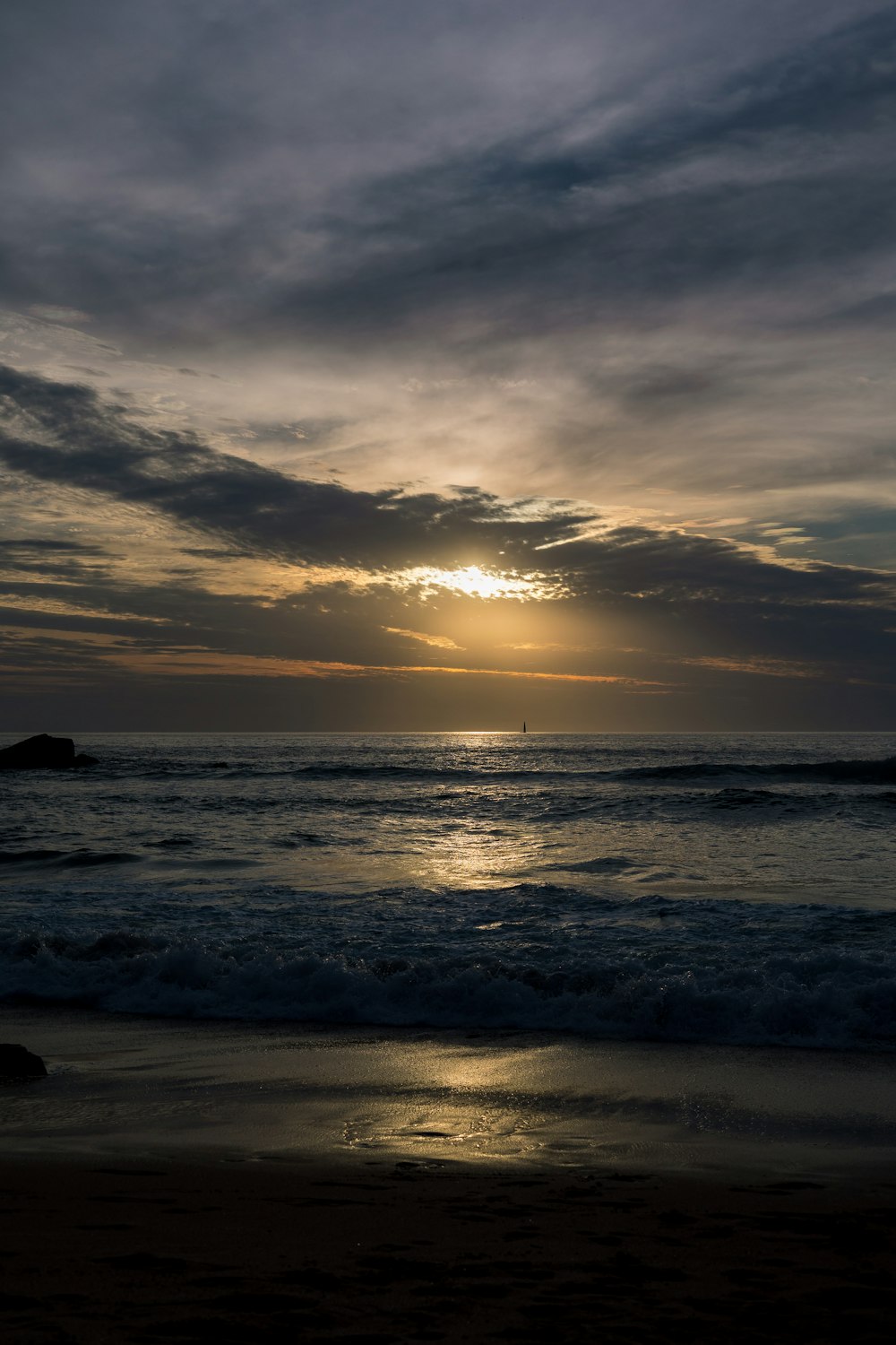 the sun is setting over the ocean on a cloudy day