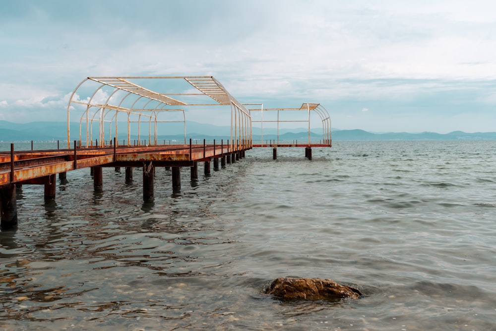 a long wooden dock with a rock in the middle of the water