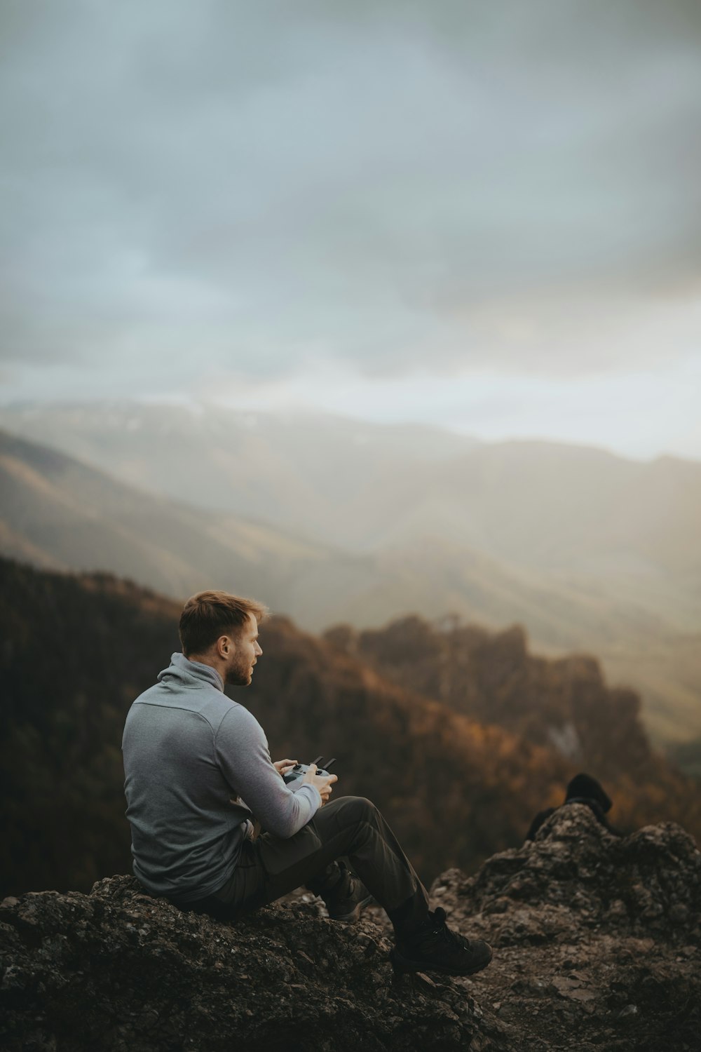 a man sitting on top of a mountain next to a bird