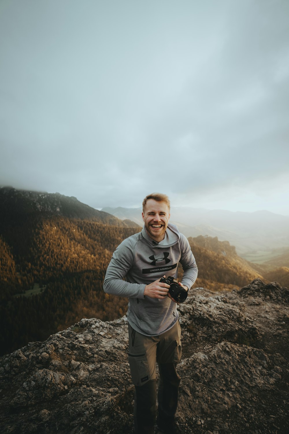 a man standing on top of a mountain holding a camera