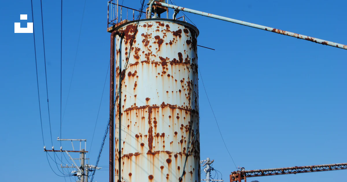A rusted metal tower with power lines in the background photo – Free ...